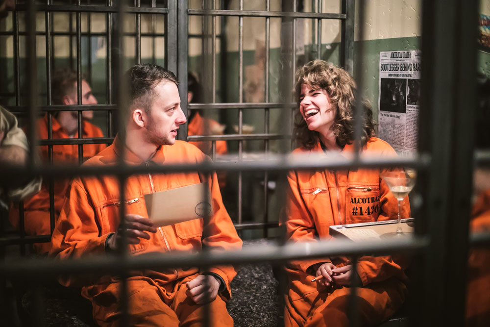 Couple enjoying cocktails during date night at Alcotraz - immersive and interactive prison-themed cocktail bar experience.