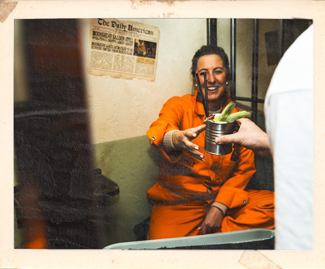 Inmate enjoying cocktails during birthday celebration at Alcotraz - immersive prison bar experience.