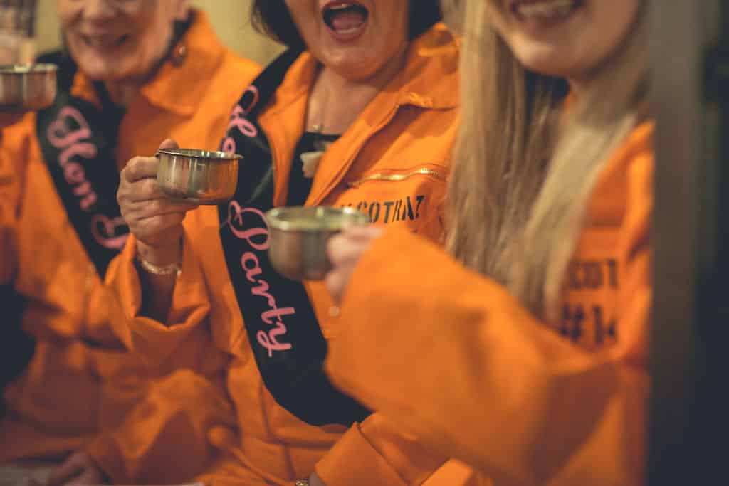 Hen party inmates with cocktails at Alcotraz - immersive prison-themed cocktail bar experience with theatrical elements.